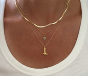 Gold necklaces with a turquoise sun pendant and boot pendant necklace on a mdoel wearing a white top